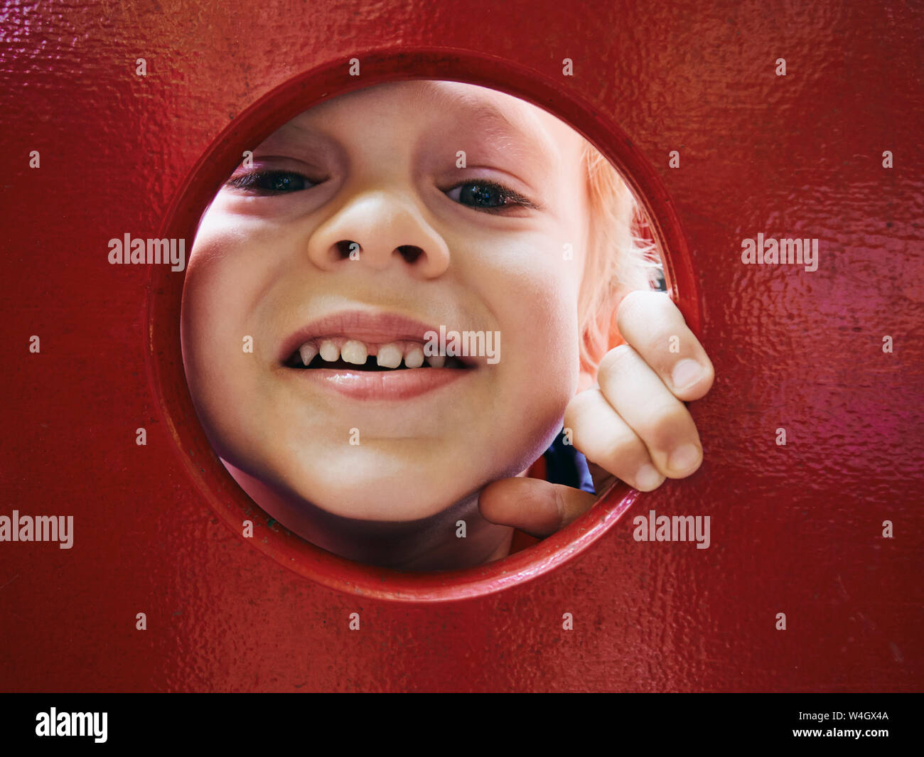 Portrait of smiling little boy looking through hole on playground Stock Photo