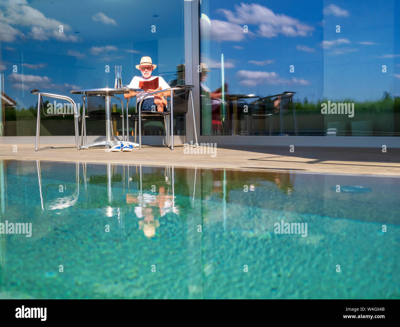 Senior man reading e-book at swimming pool Stock Photo
