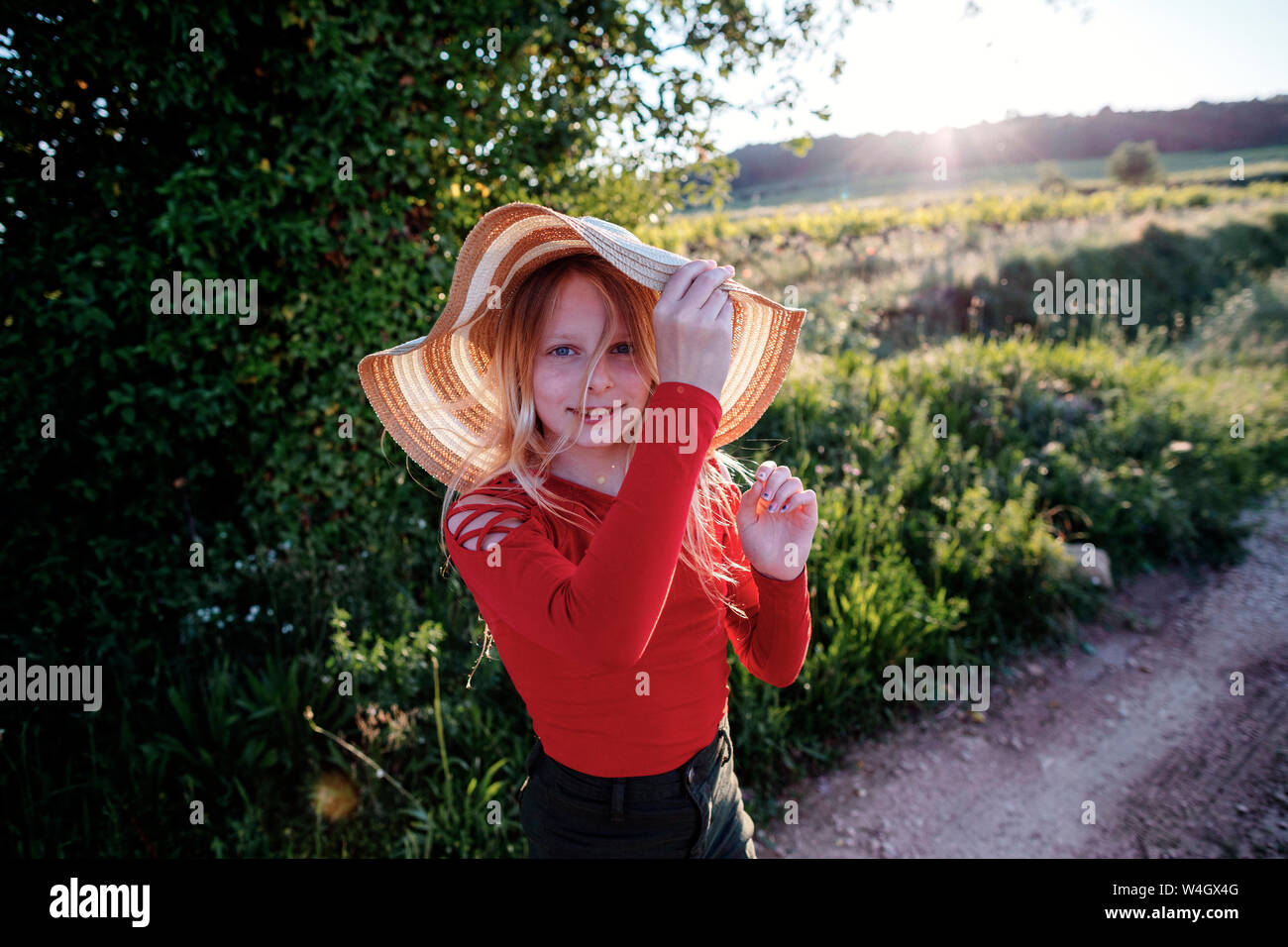 Little girl wearing a sun hat, standing by a field Stock Photo
