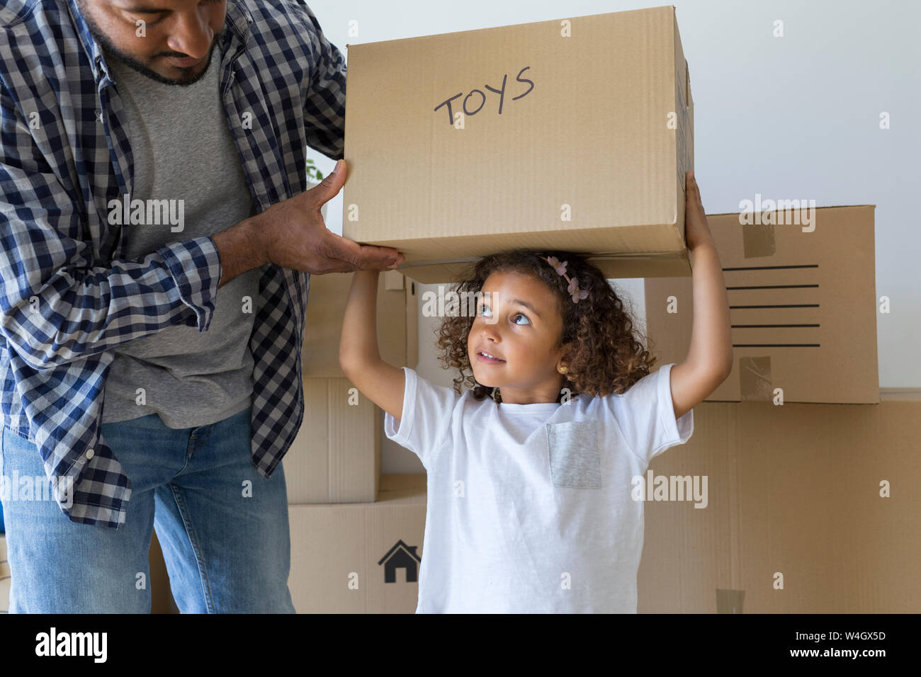 Father with daughter carrying cardboard box at new home Stock Photo