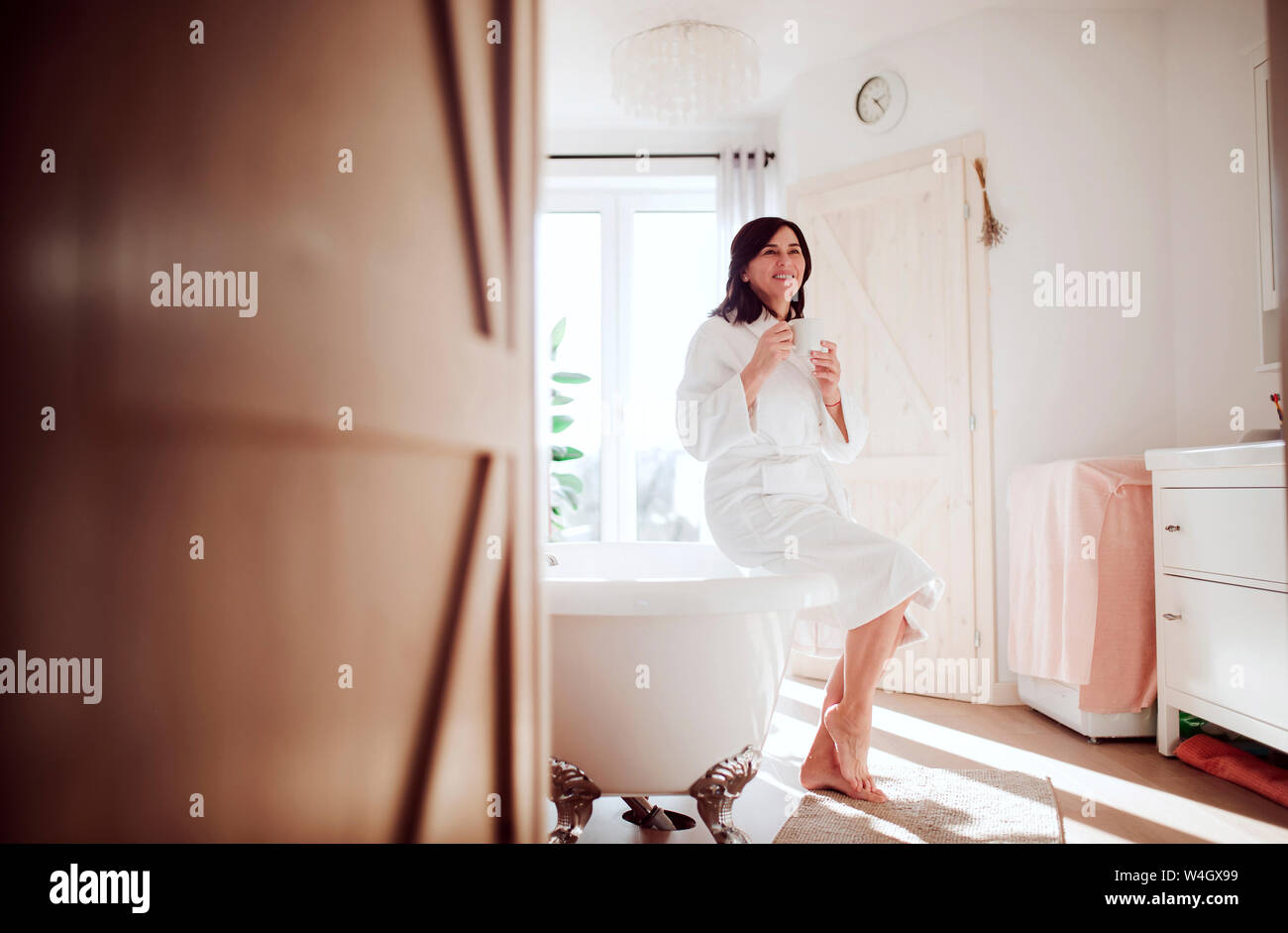 Mature woman sitting on bath tub, drinking coffee Stock Photo - Alamy