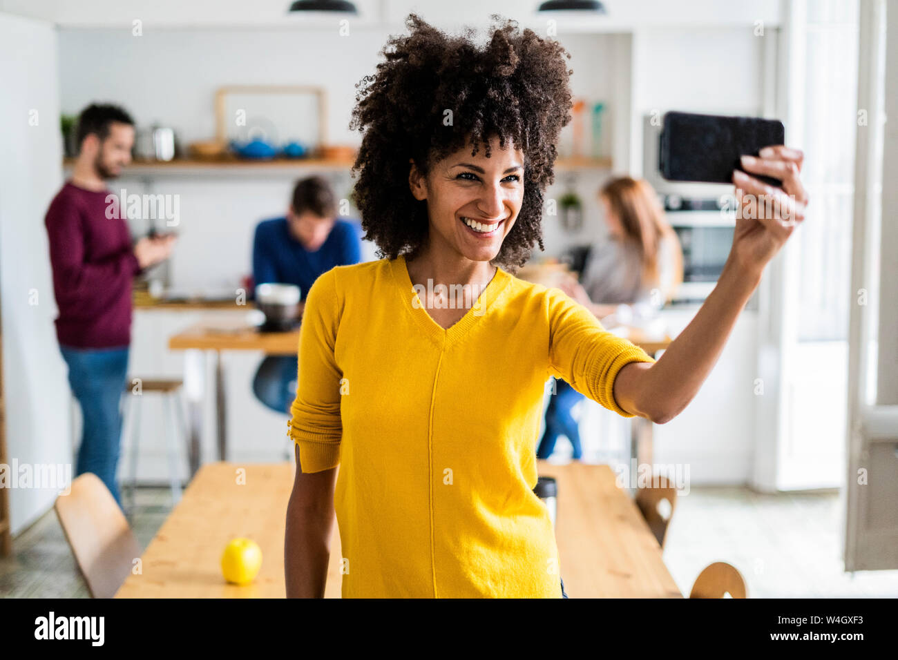 Happy woman taking a selfie at home with friends in background Stock ...
