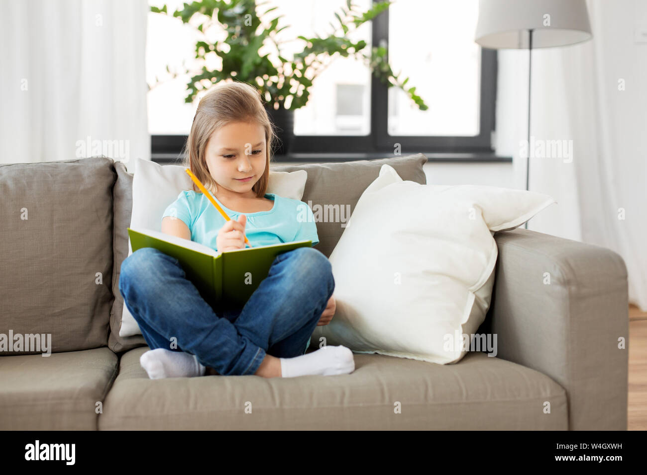 little girl with diary sitting on sofa at home Stock Photo Alamy