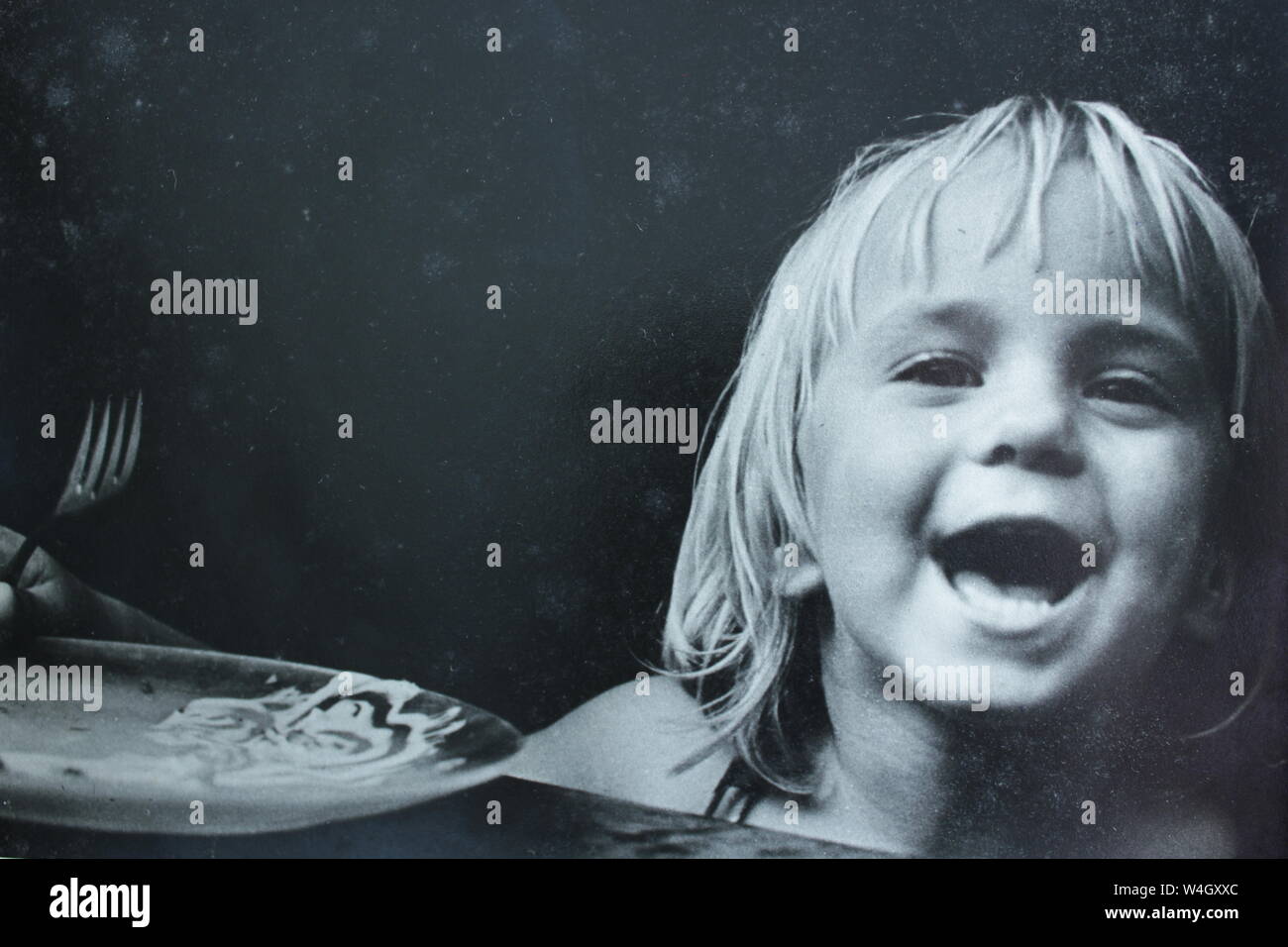 Fine black and white art photography from the 1970s of little blond Swedish girl laughing at the camera. Stock Photo