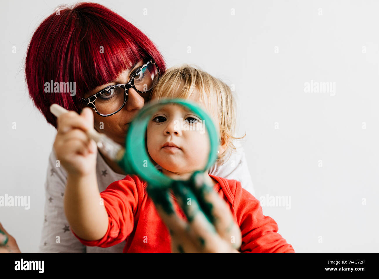 Mother and daughter doing crafts at home painting cardboard roll Stock