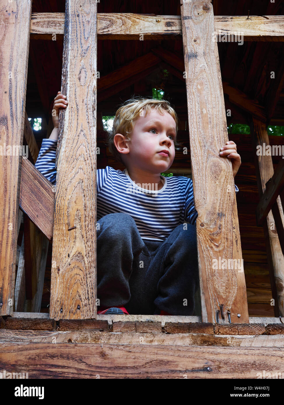 Portrait of littleboy crouching on climbing frame Stock Photo
