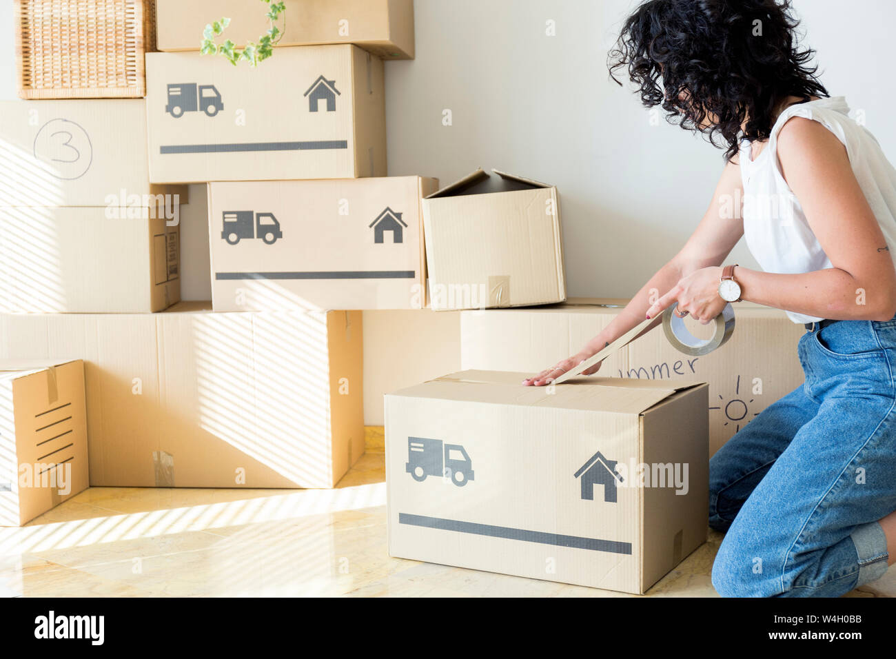 Young woman moving out taping cardboard box Stock Photo