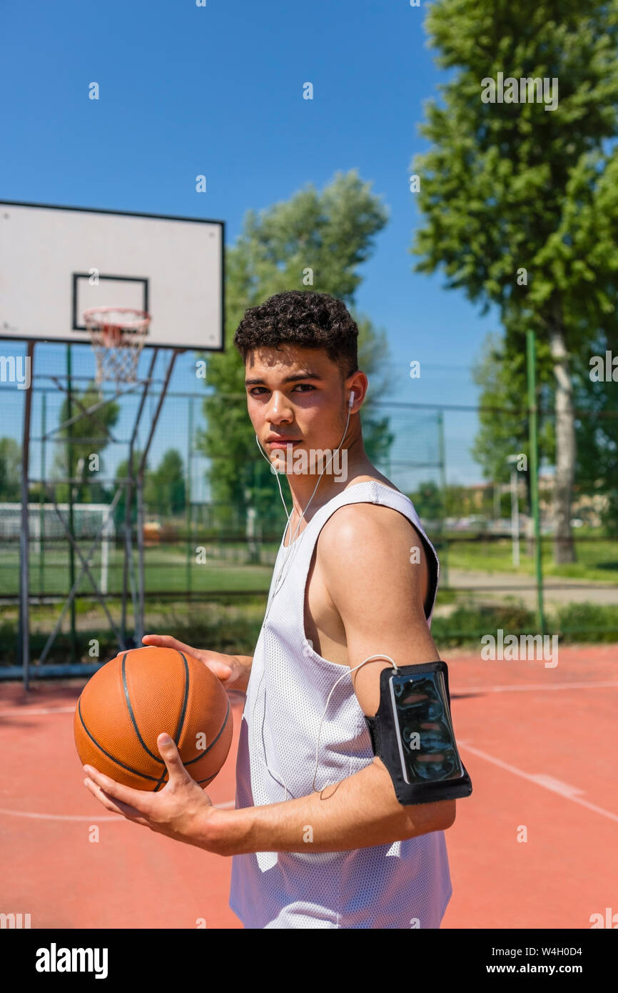 Young man playing basketball, smartphone in arm pocket Stock Photo