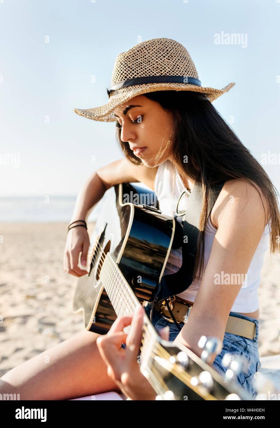 Young woman playing guitar on the beach Stock Photo