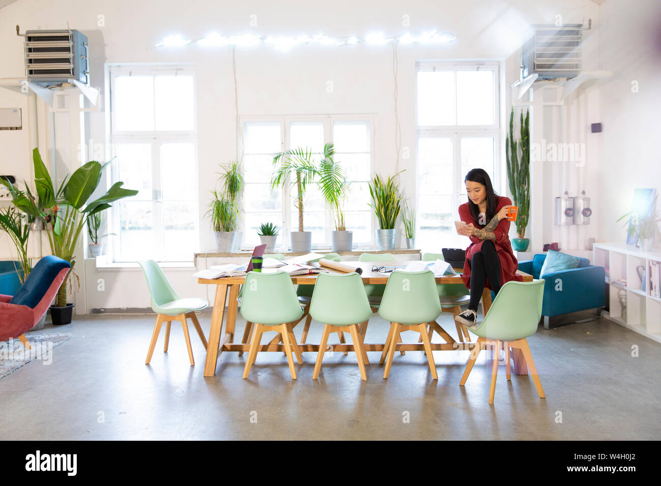 Woman using cell phone in modern office Stock Photo