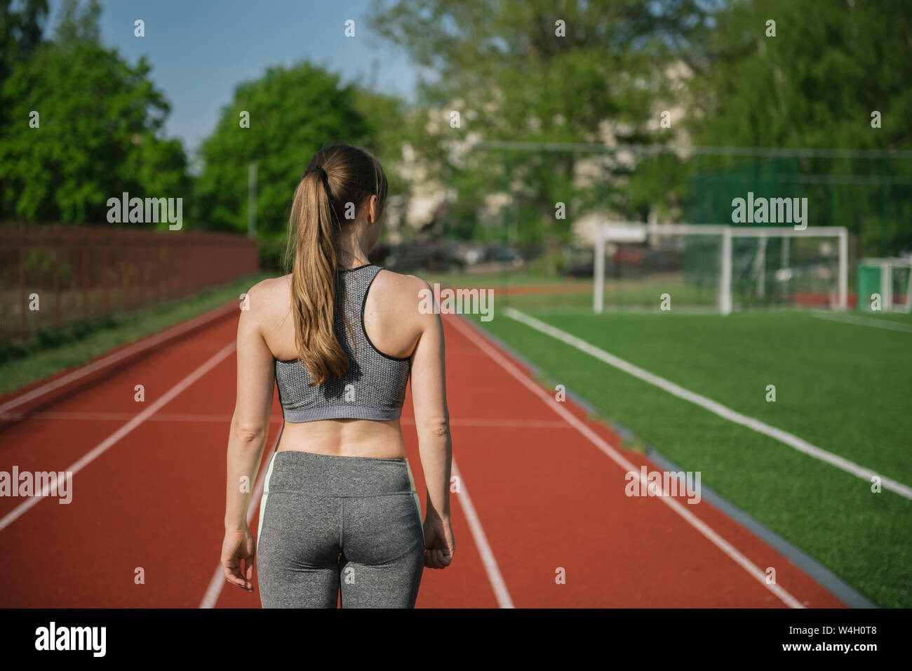 Rear view of sportswoman standing on racetrack in stadium Stock Photo
