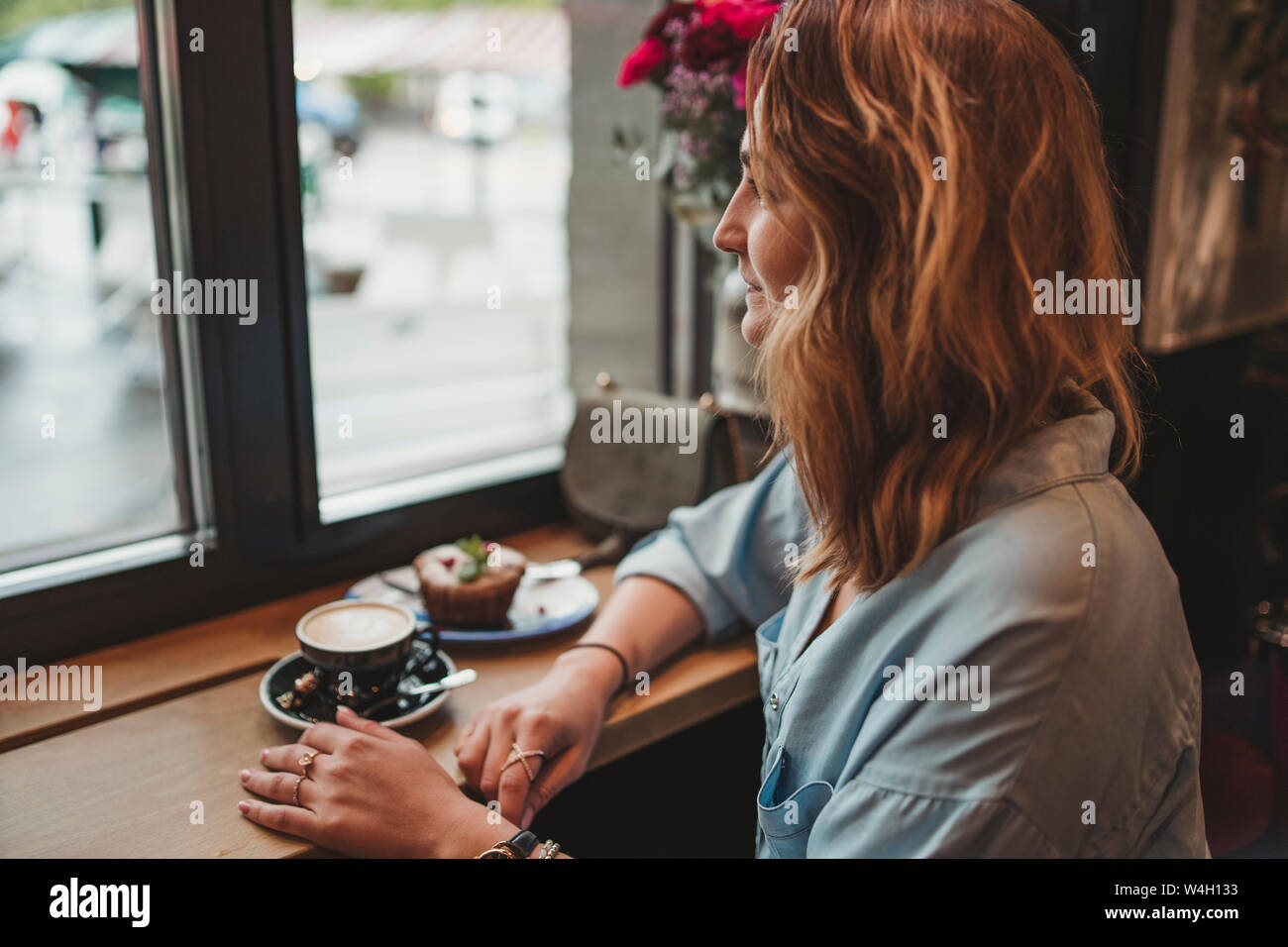Young woman sitting at the window in a cafe Stock Photo - Alamy