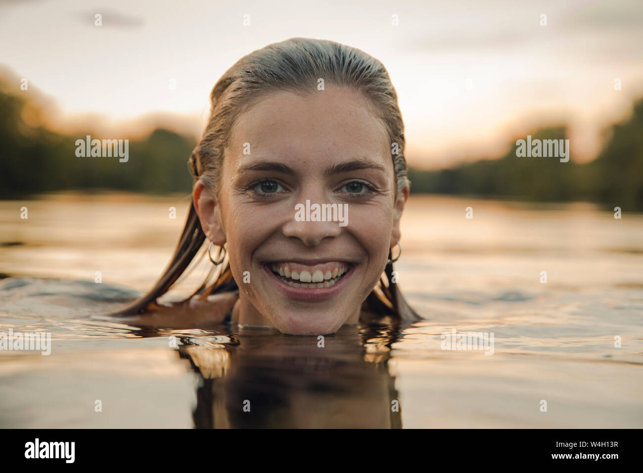 Young woman swimming in lake at sunset Stock Photo