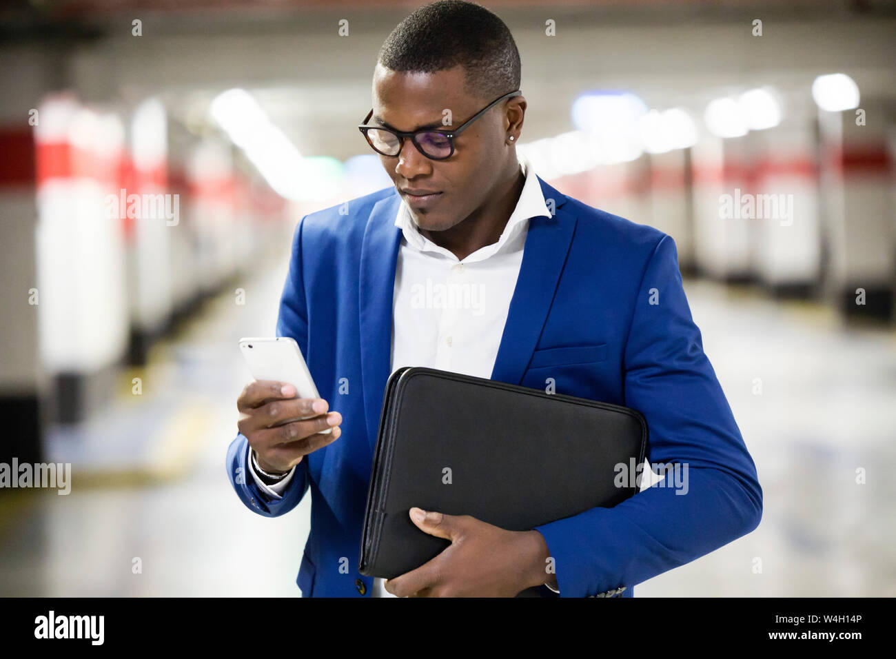 Young businessman wearing blue suit jacket and using smartphone Stock Photo
