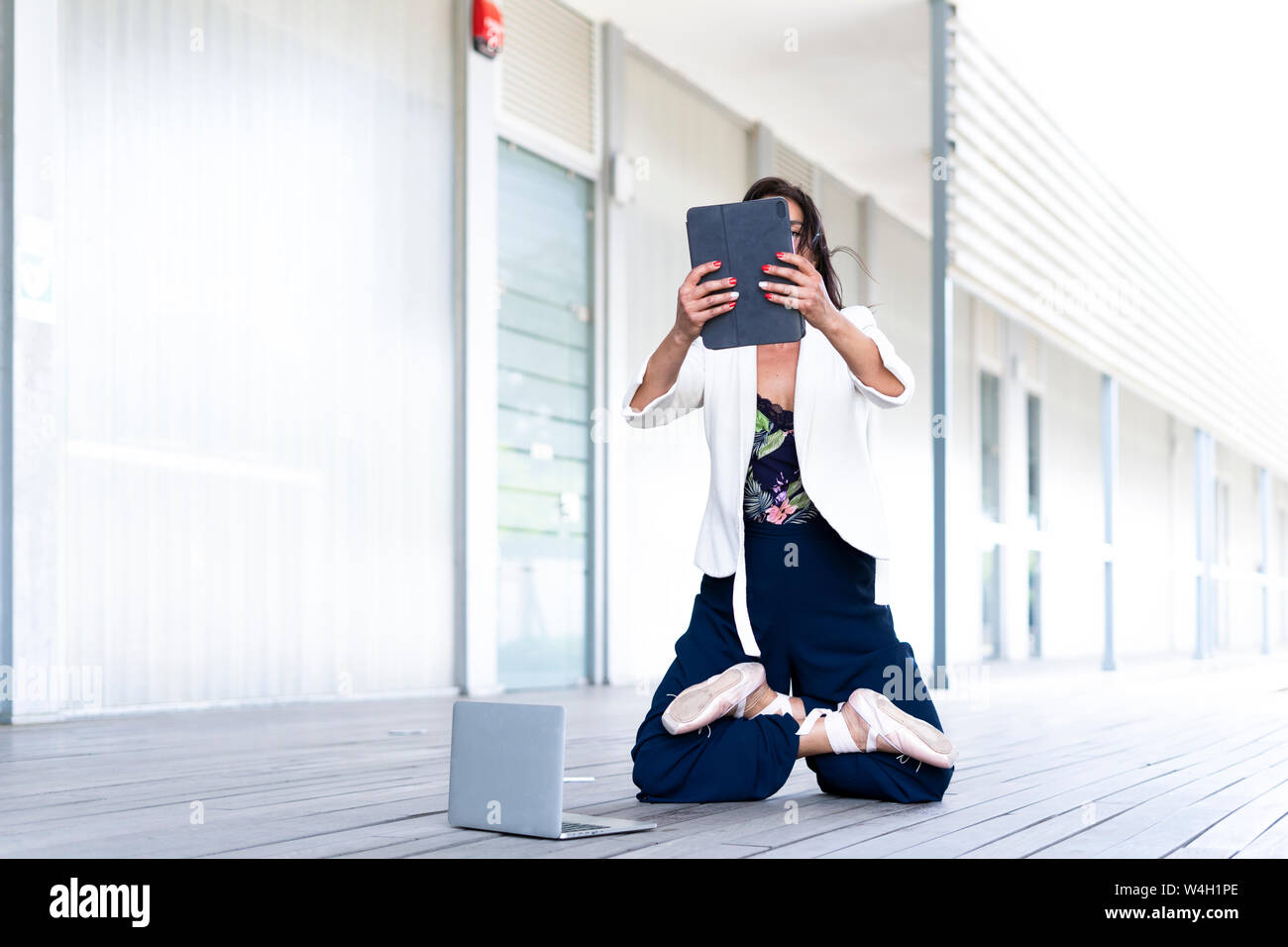 Female balett dancer kneeling on the ground, using tablet Stock Photo