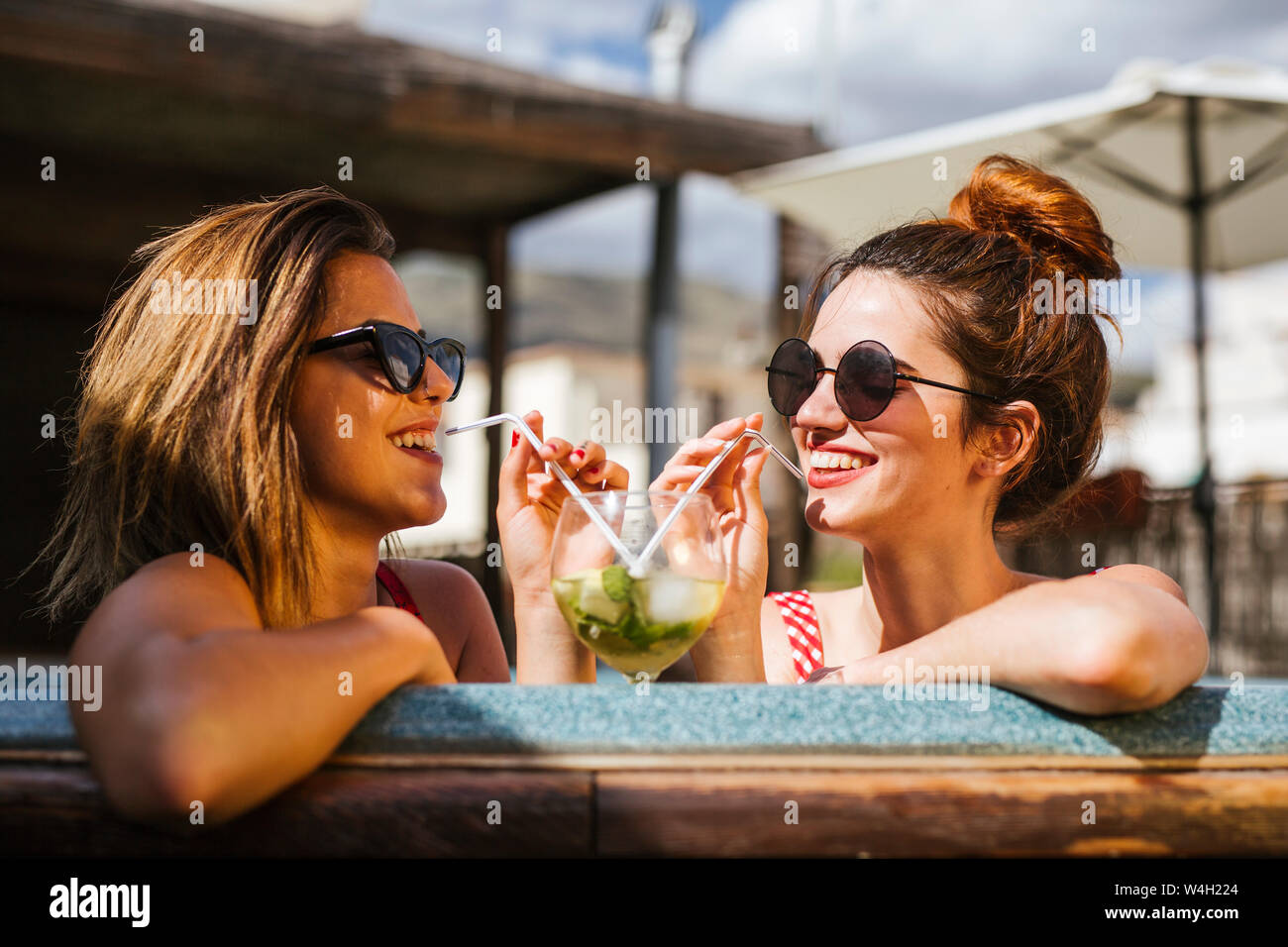 Two women having a drink in a jacuzzi Stock Photo