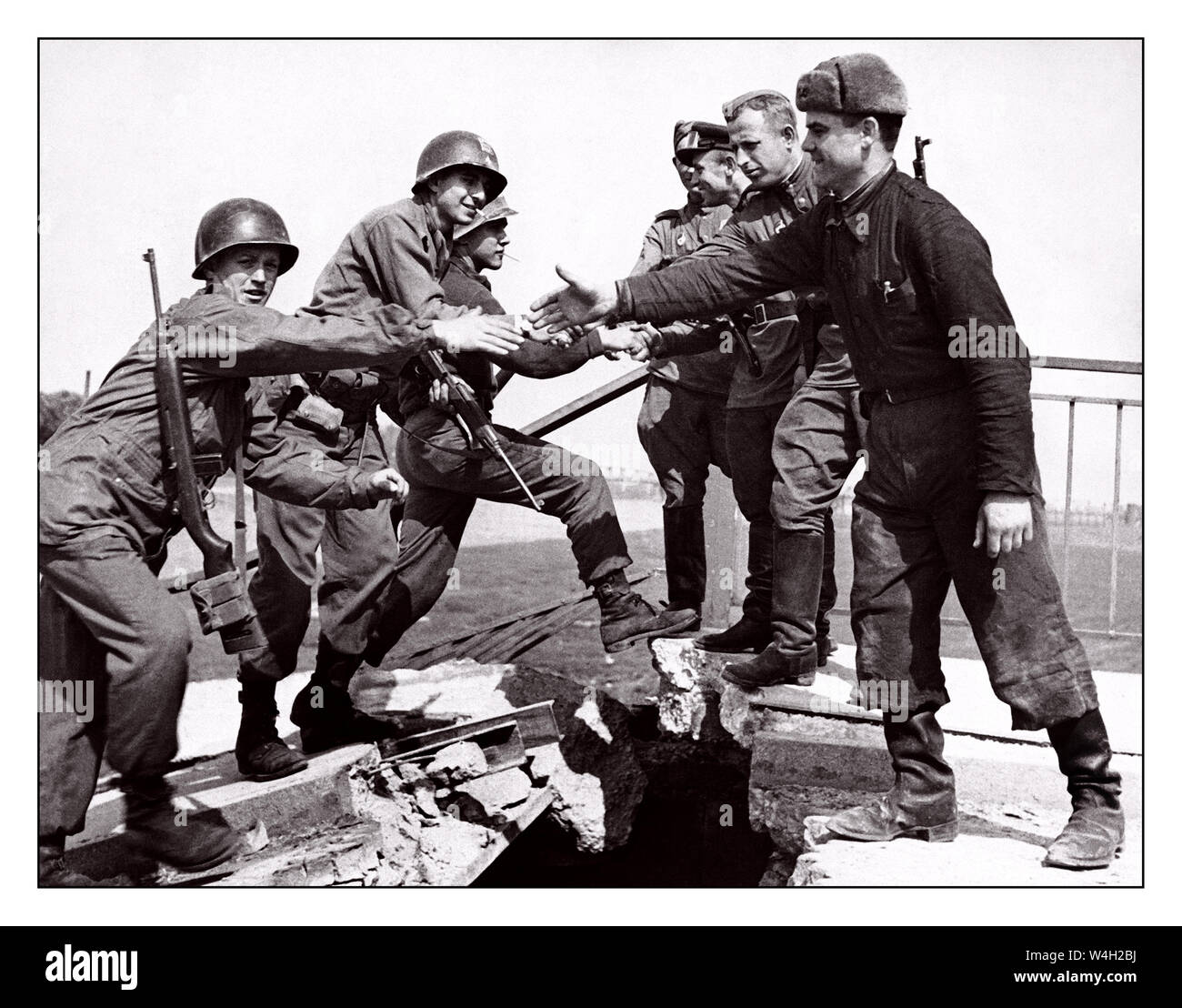 TORGAU East meets West WW2 image of U.S. and Soviet troops meeting on the bridge over the Elbe River at Torgau on April 26, 1945.  The famous “handshake of Torgau” photograph that signified east meeting west near the end of World War II  U S First Army crossing damaged bridge over the River Elbe Torgau Saxony Germany U.S. Army photo Stock Photo