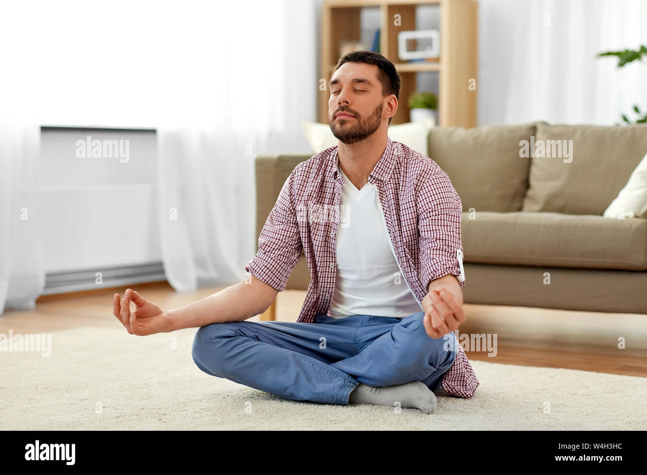 man meditating in lotus pose at home Stock Photo - Alamy