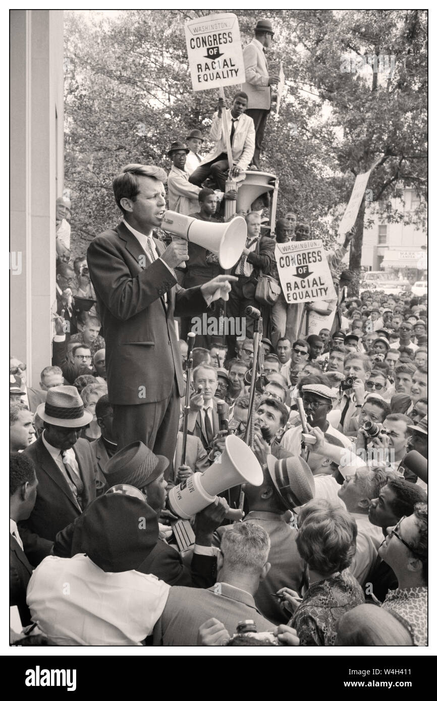 Vintage 1960's image Attorney General Robert F. Kennedy speaking to a crowd of African Americans and whites through a megaphone outside the Justice Department; Poster sign for 'Congress of Racial Equality' is prominently displayed. 14 June 1963. Stock Photo