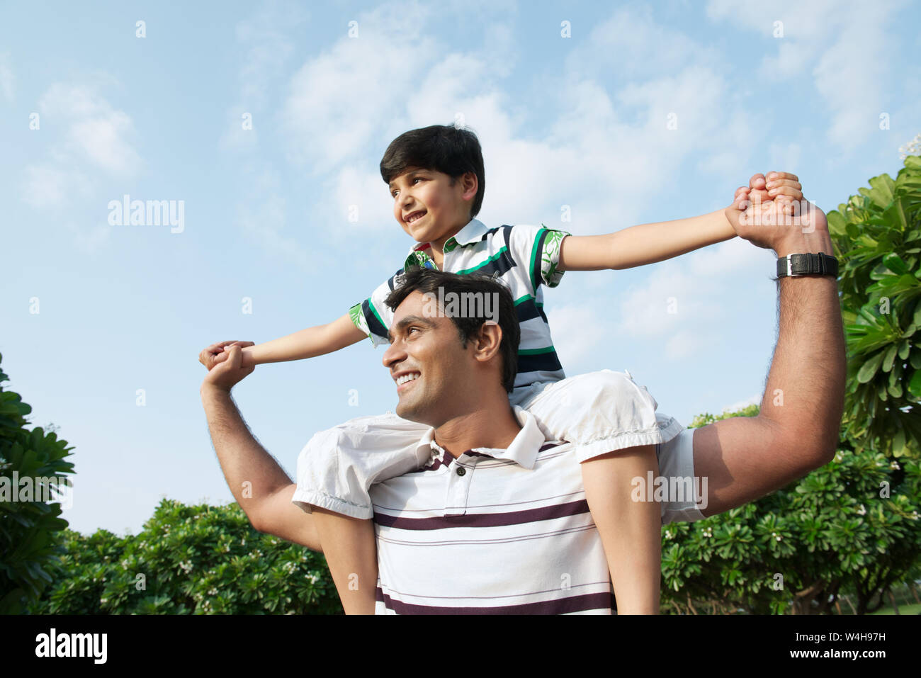 Man carrying his son on his shoulders and smiling Stock Photo - Alamy