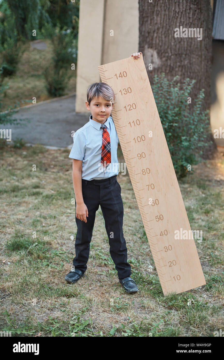 Schoolboy with big ruler standing on wooden background. Farewell Bell ...