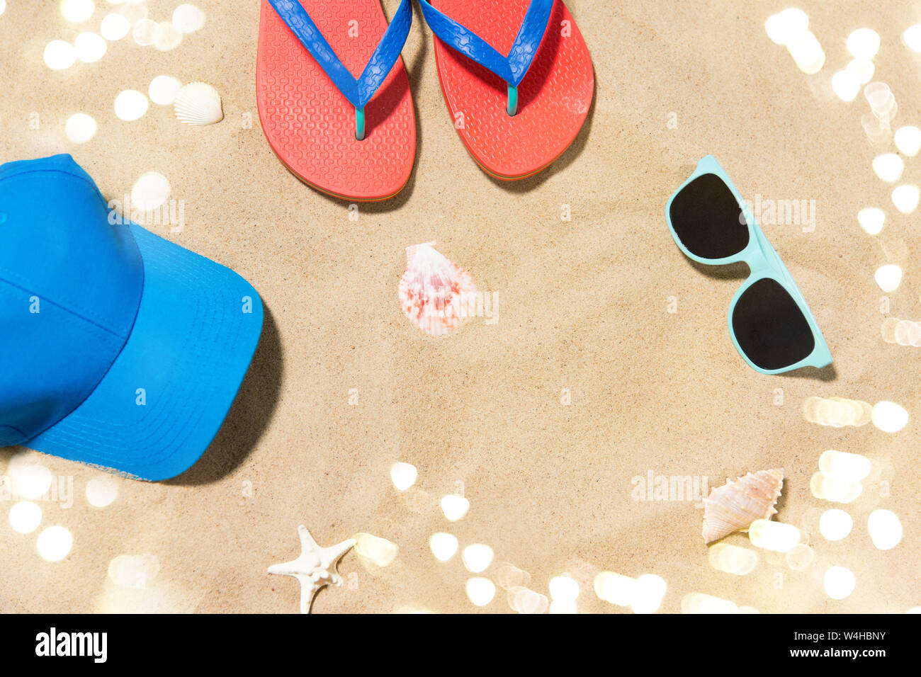 cap, flip flops, shades and on shells beach sand Stock Photo - Alamy