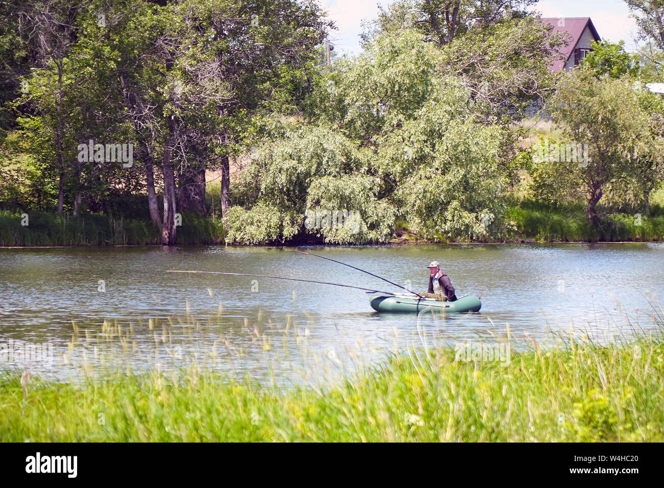 Fisherman in a boat fishing on the lake Stock Photo - Alamy
