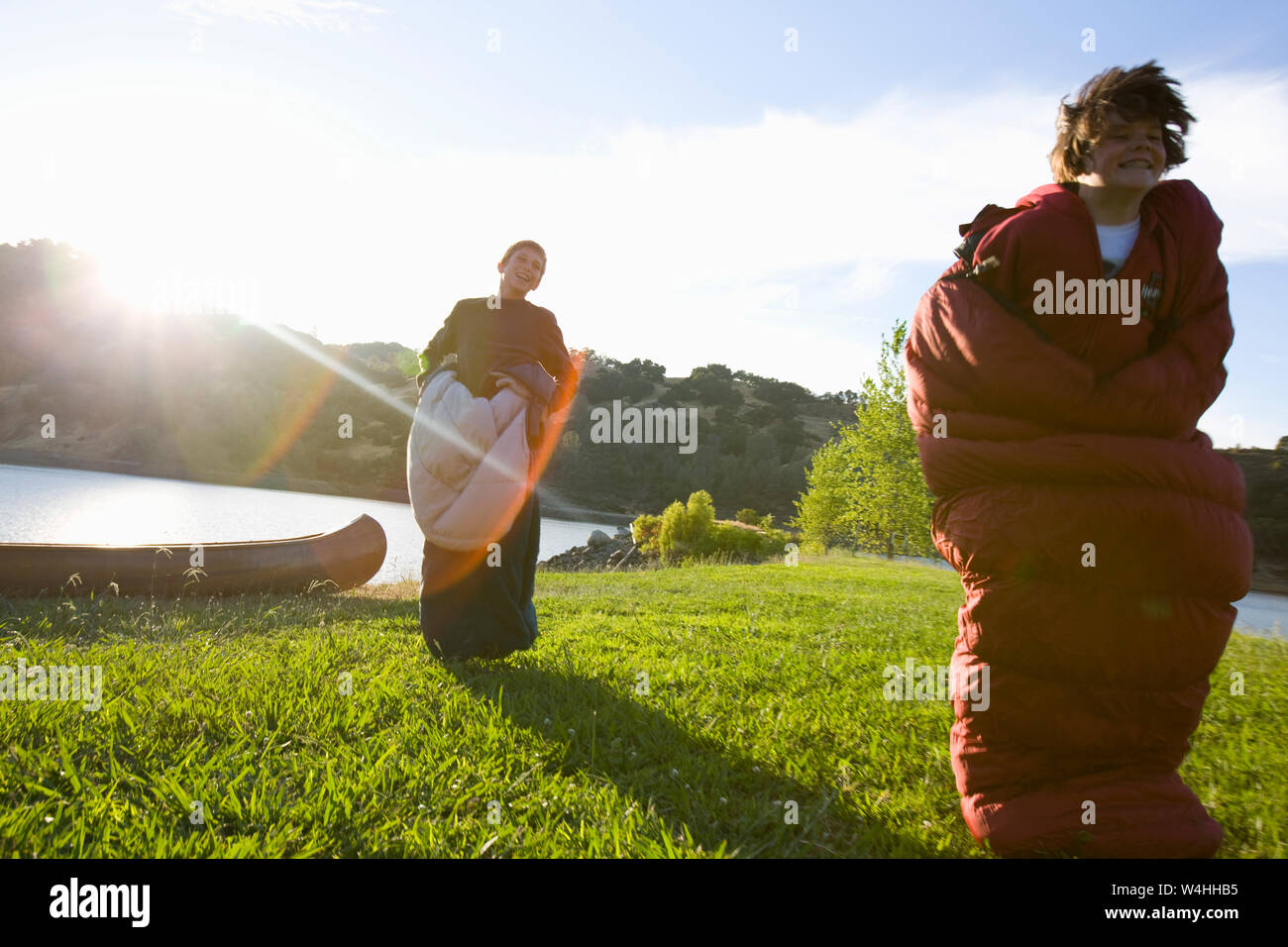 Two boys having fun while jumping along a grassy lawn inside sleeping