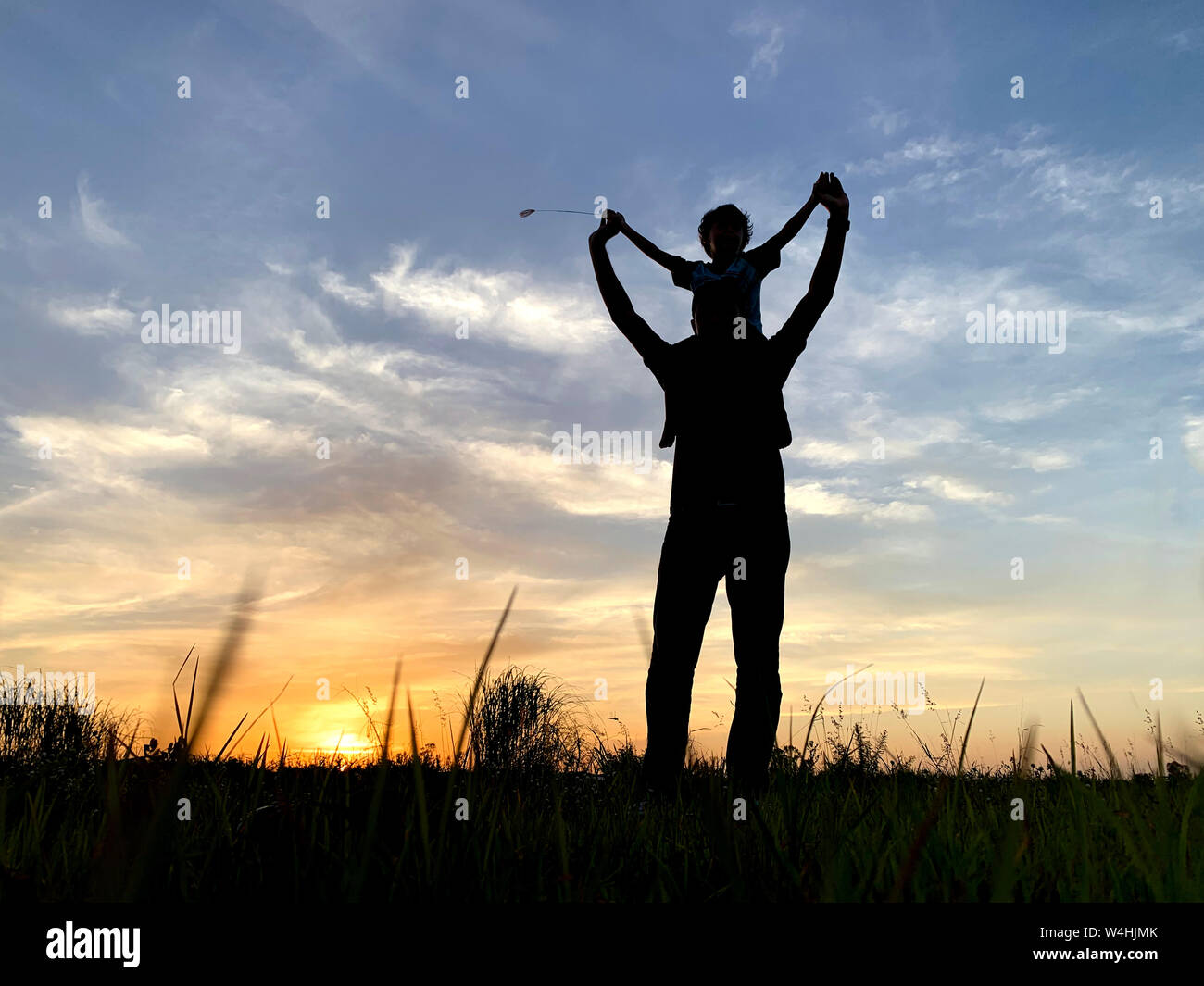 Silhouette Father Carrying Son Against Sky During Sunset Stock Photo