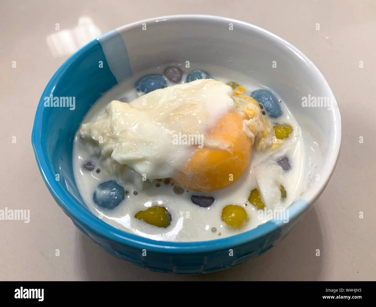 Sticky rice pearls in coconut milk with poached egg in light syrup Stock Photo