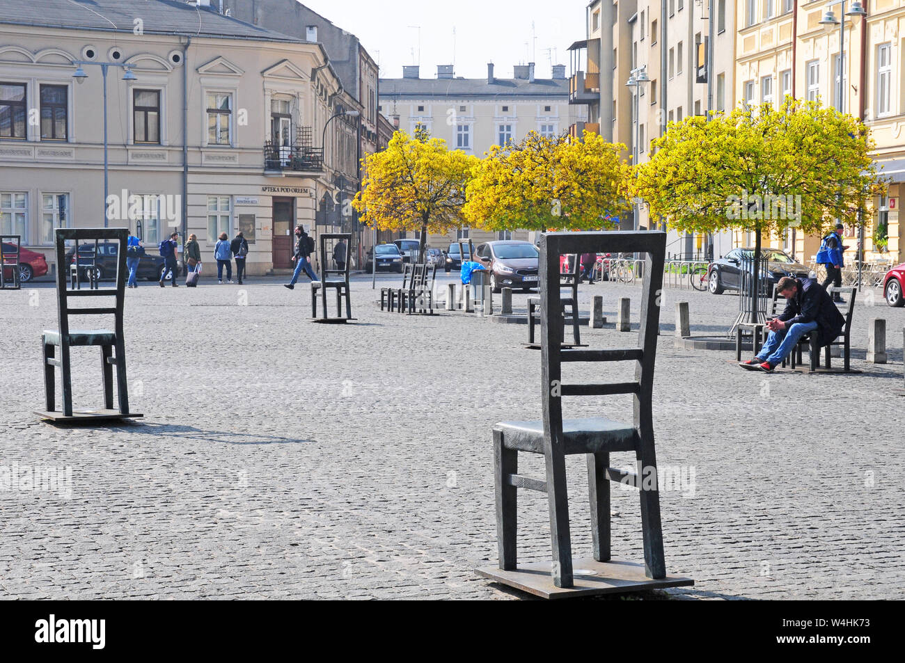 Chairs in the ghetto Heroes Square Monument with the Apteka Pod orlem Pharmacy Museum behind. Stock Photo