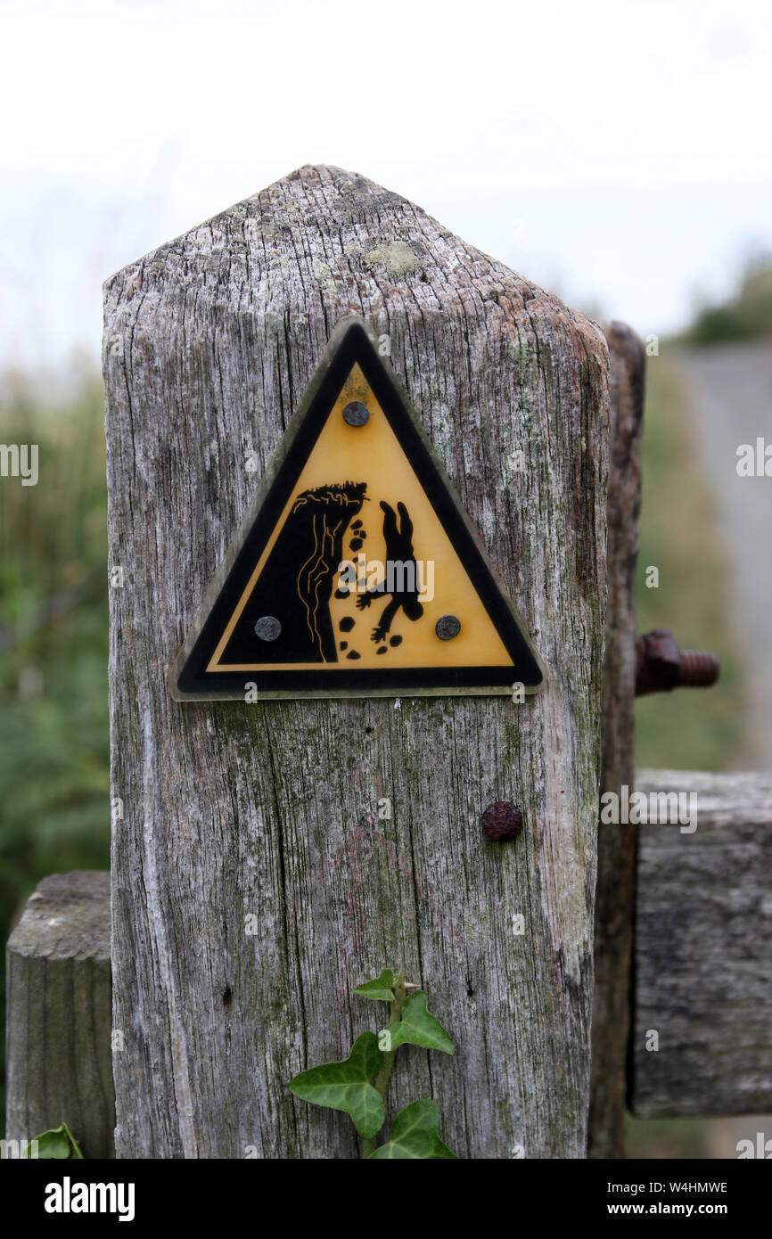 Black and yellow warning triangle sign on a post advising of the danger of erosion and cliff falls Stock Photo