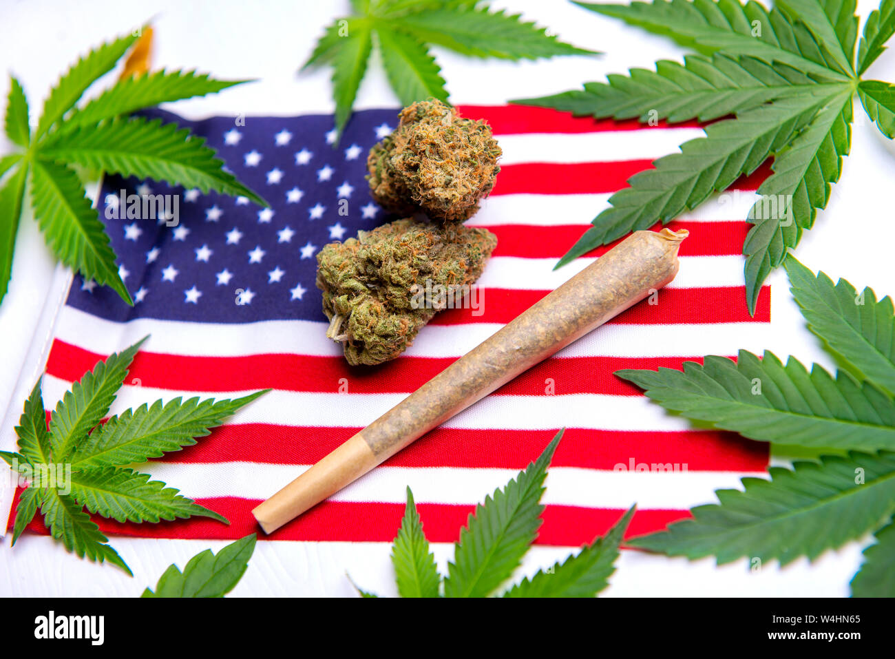 Cannabis leaves, dry nugs and rolled joint over the american flag