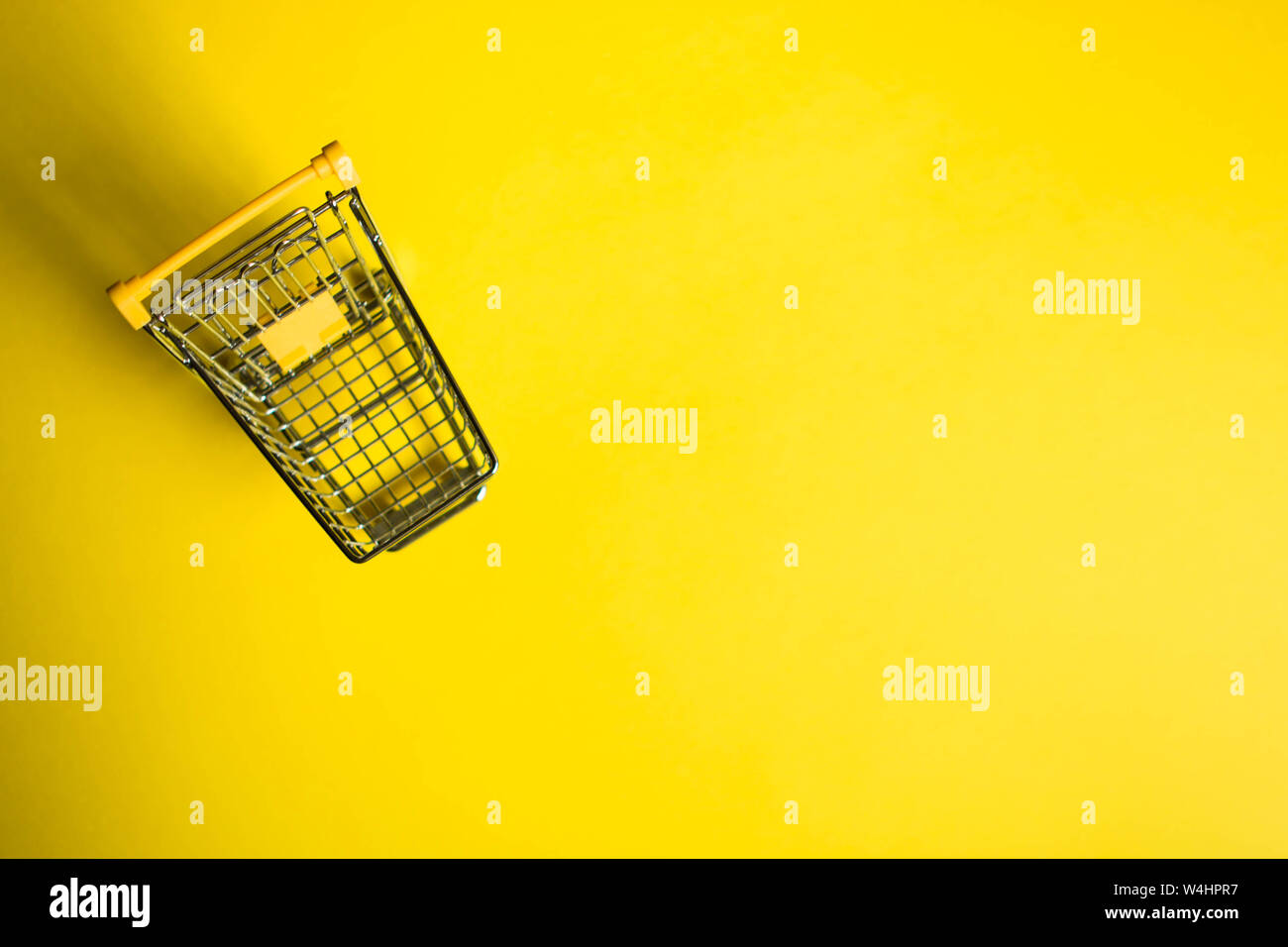 Top view of an small trolley in a yellow background. Space for text. Sale concept Stock Photo
