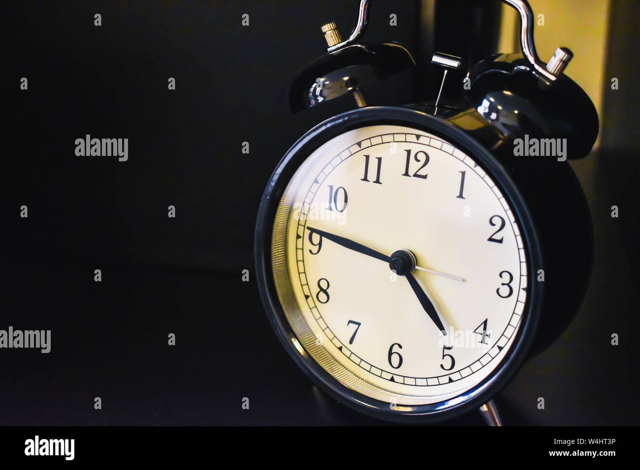 Vintage style black and white alarm clock with dark background. Stock Photo