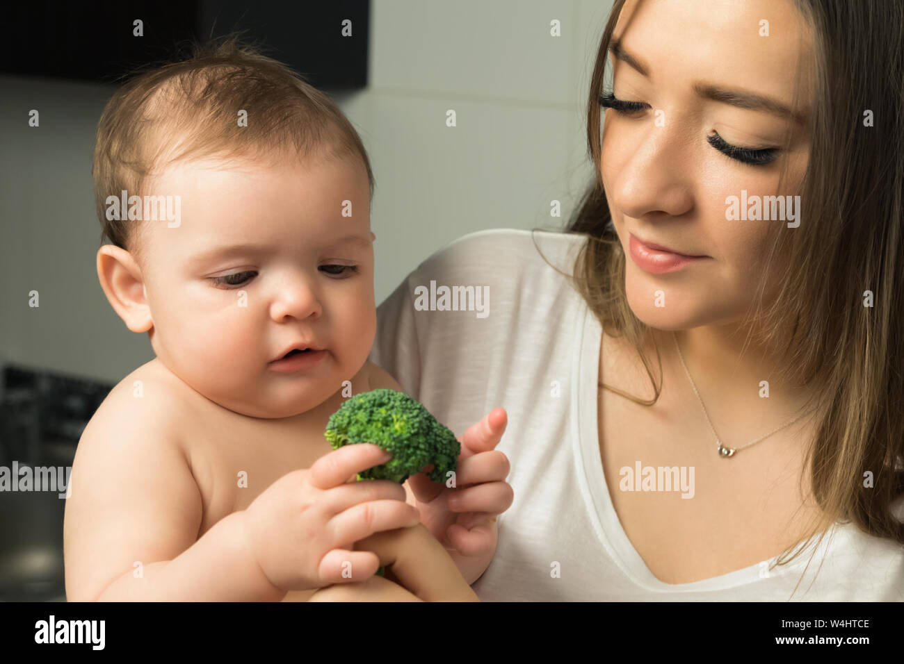 Young mother feeds baby broccoli Stock Photo Alamy