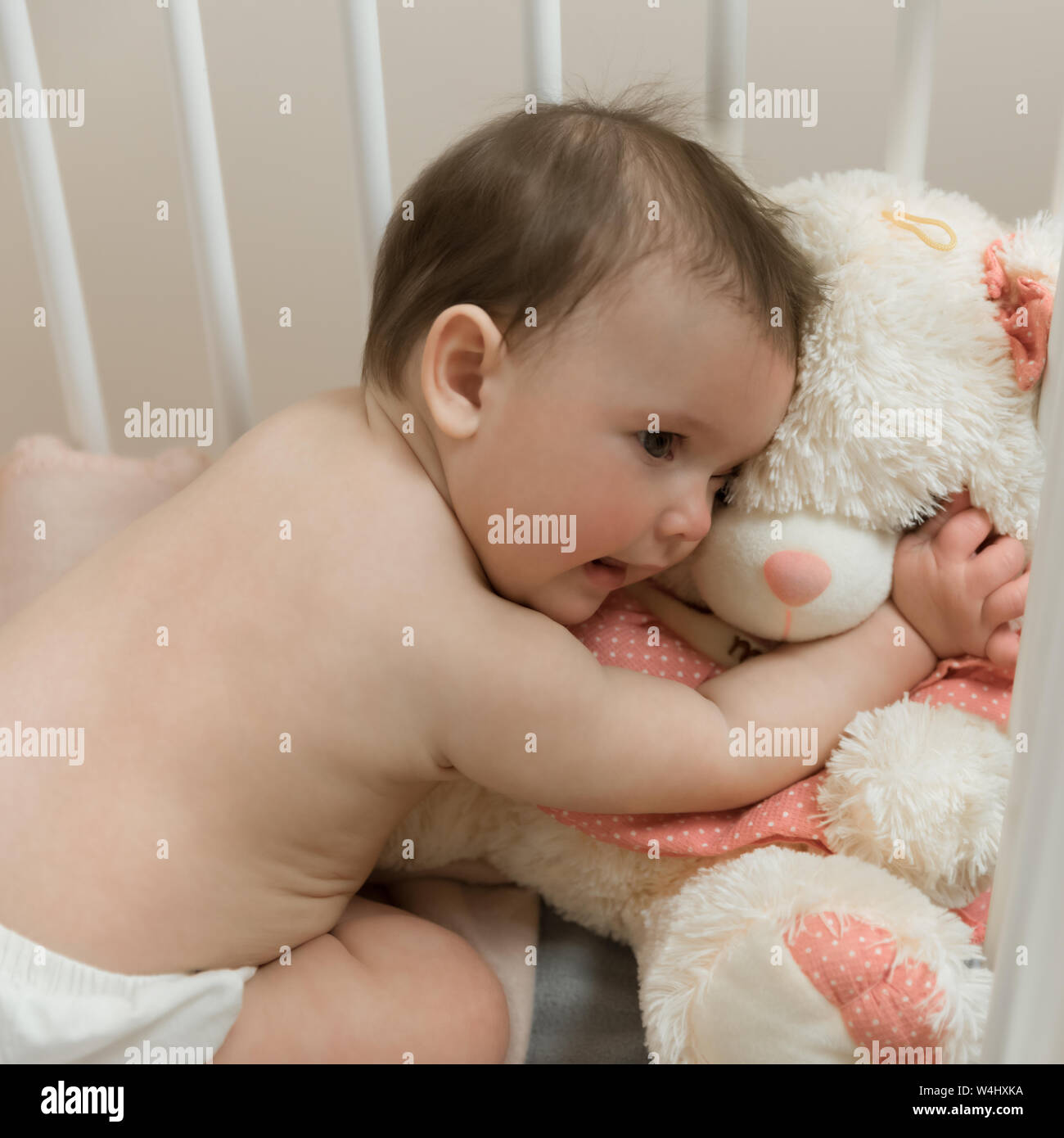 Baby girl playing with a teddy bear in a crib Stock Photo - Alamy