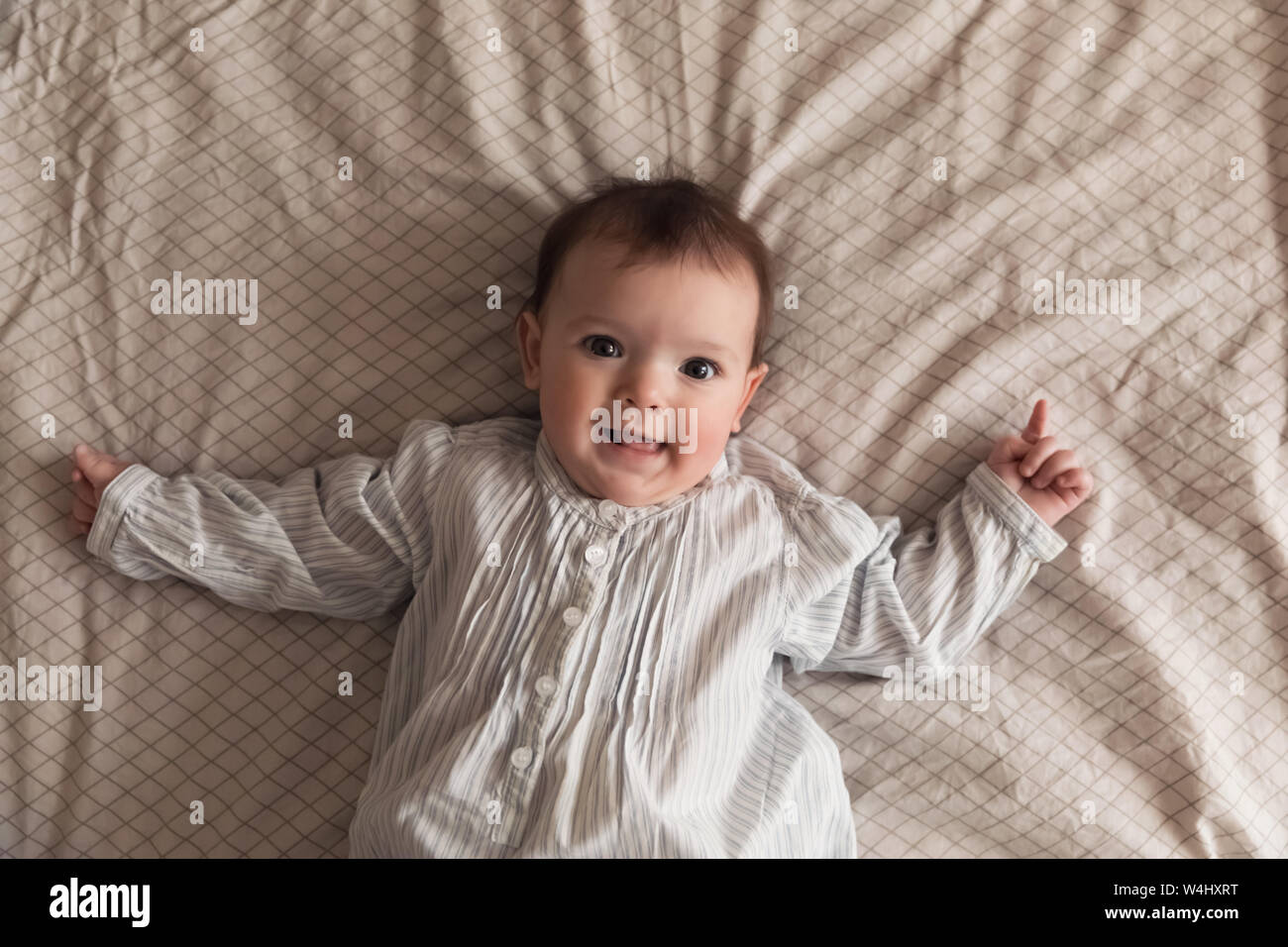 Cute newborn girl lying on the bed. The baby wants to sleep in the parent's bed. Stock Photo