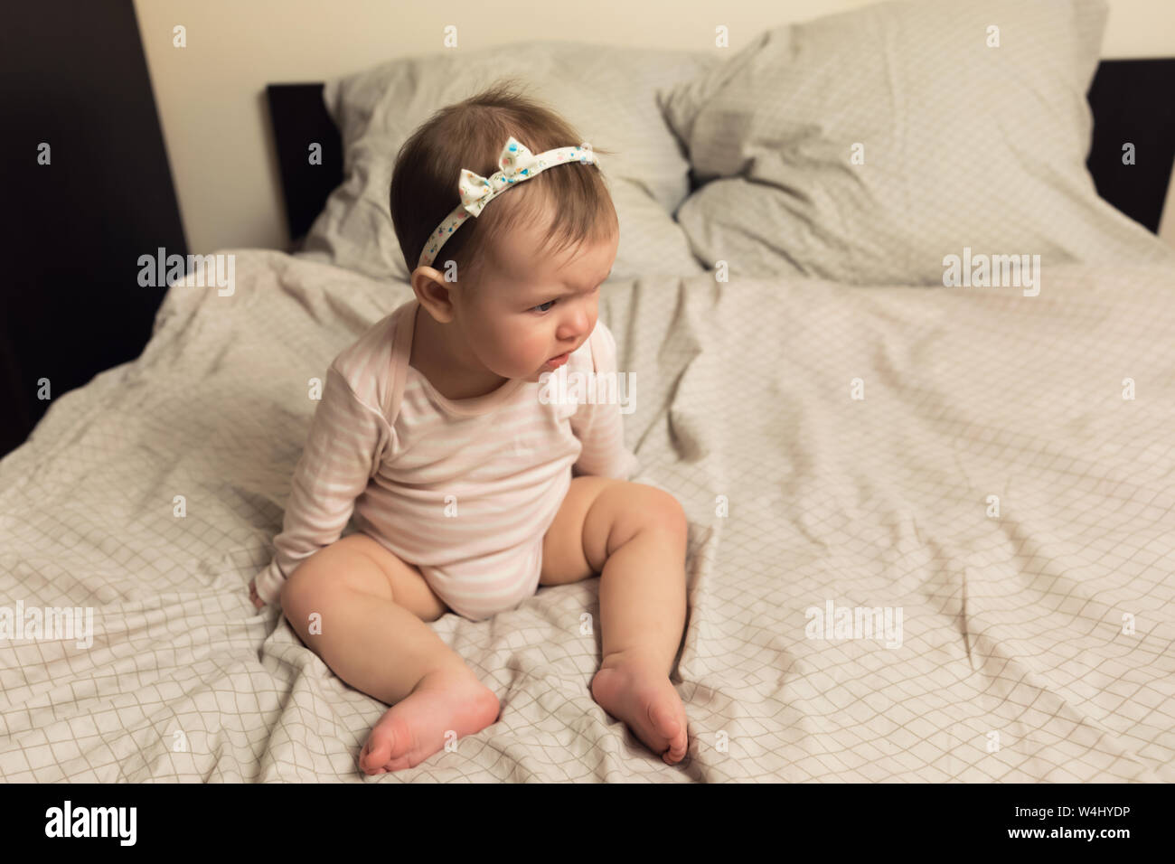 Cute newborn girl lying on the bed. The baby wants to sleep in the
