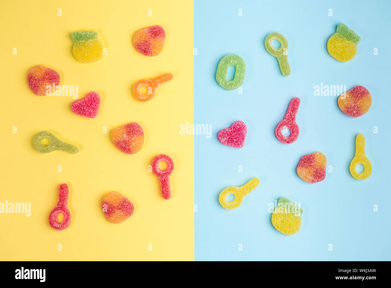 Multicolored gummy candies on yellow and blue backgrounds. Top view