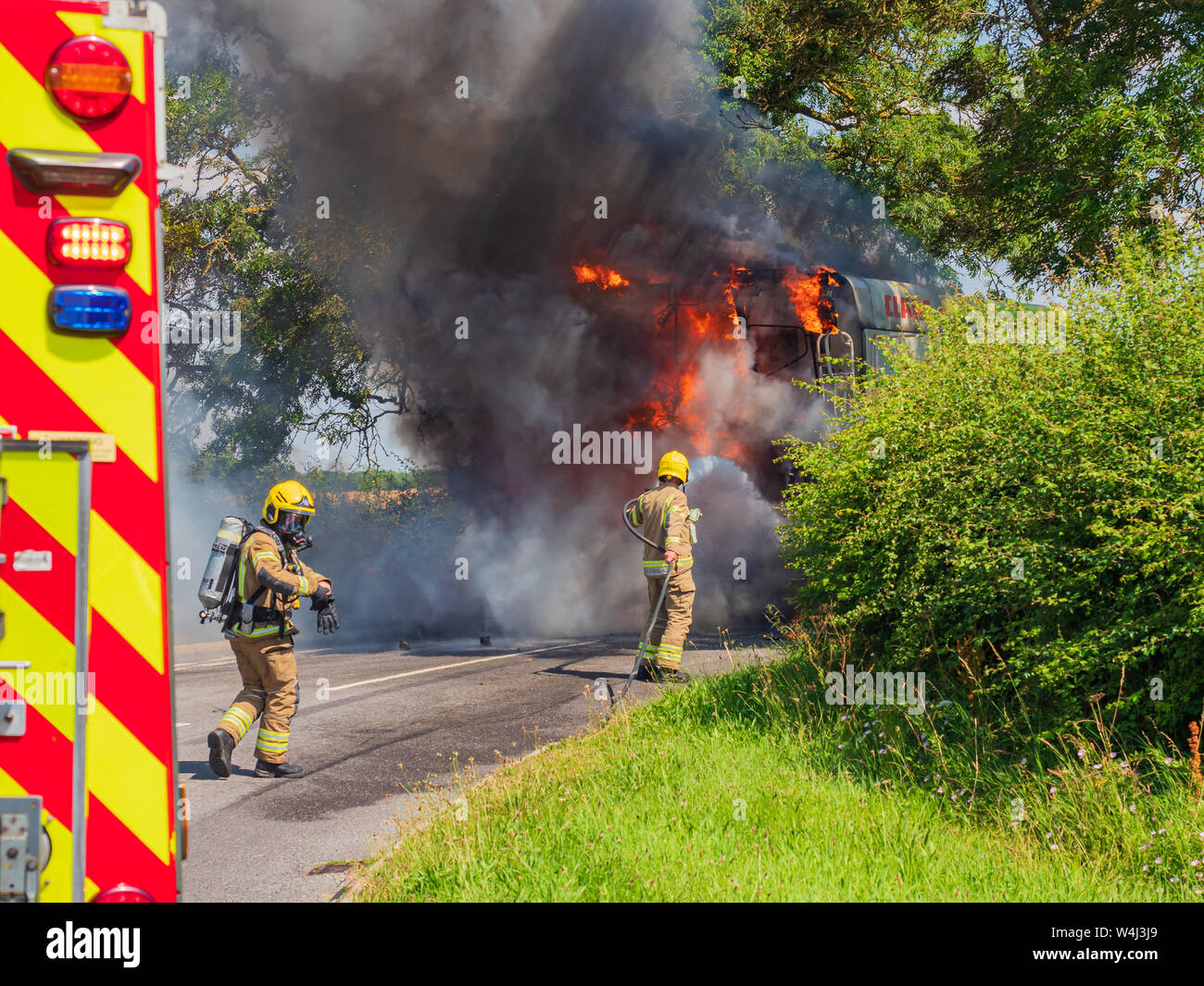 A crew from Lincolnshire Fire and Rescue wearing breathing apparatus in action at the scene of a major vehicle fire involving a Combine harvester Stock Photo