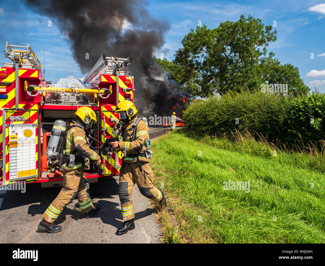 Firefighters from Lincolnshire Fire and Rescue wearing breathing apparatus in action at the scene of major vehicle fire involving a Combine harvester Stock Photo