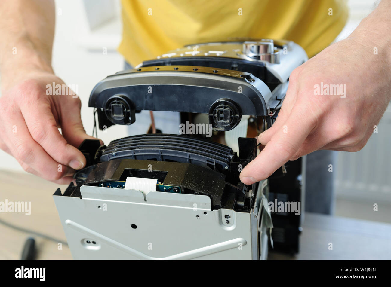 A man is repairing the musical system.  He is pulling the CD changer to outside. Stock Photo