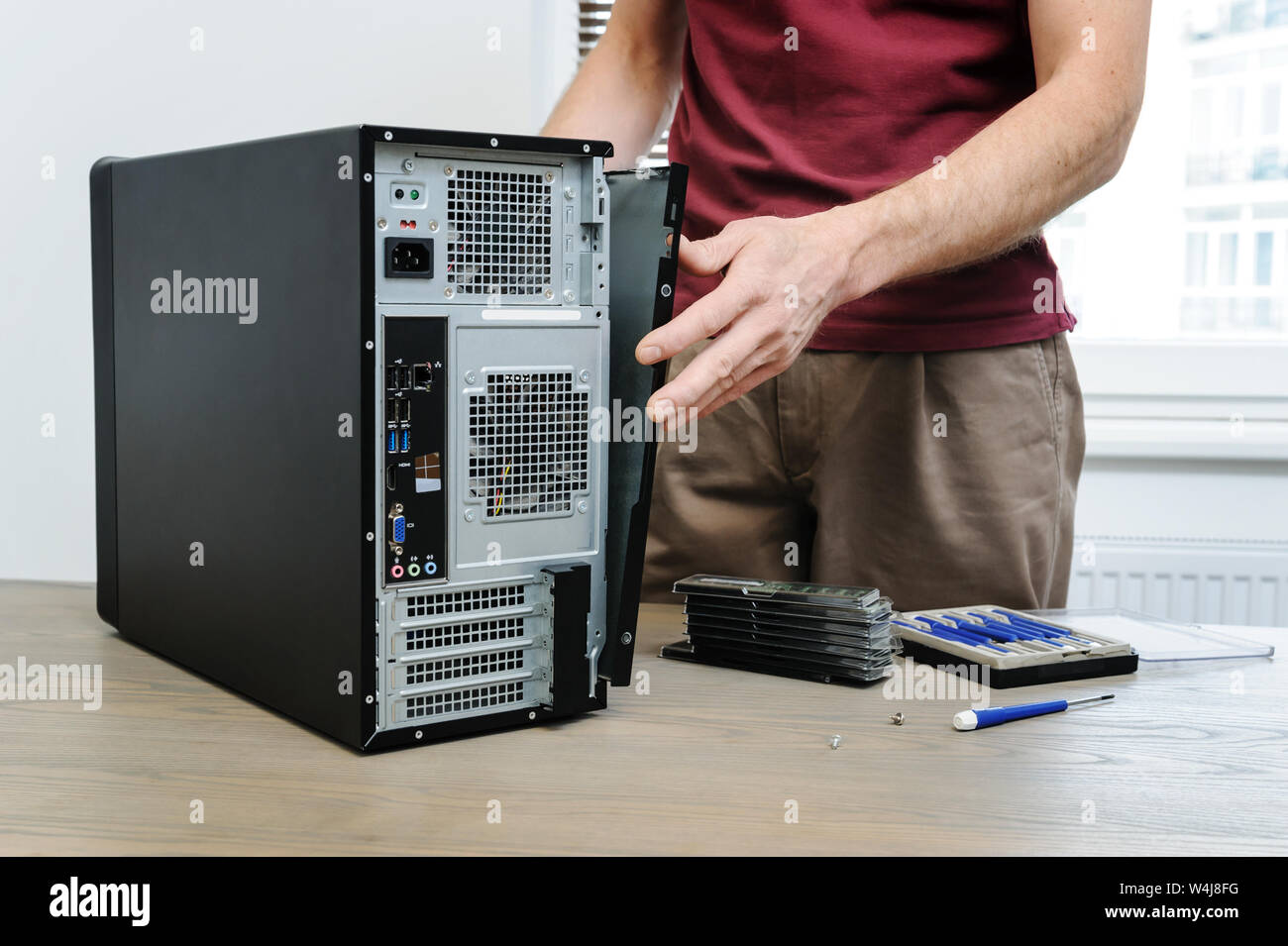 A man is removing the side panel from the computer for access inside. Stock Photo
