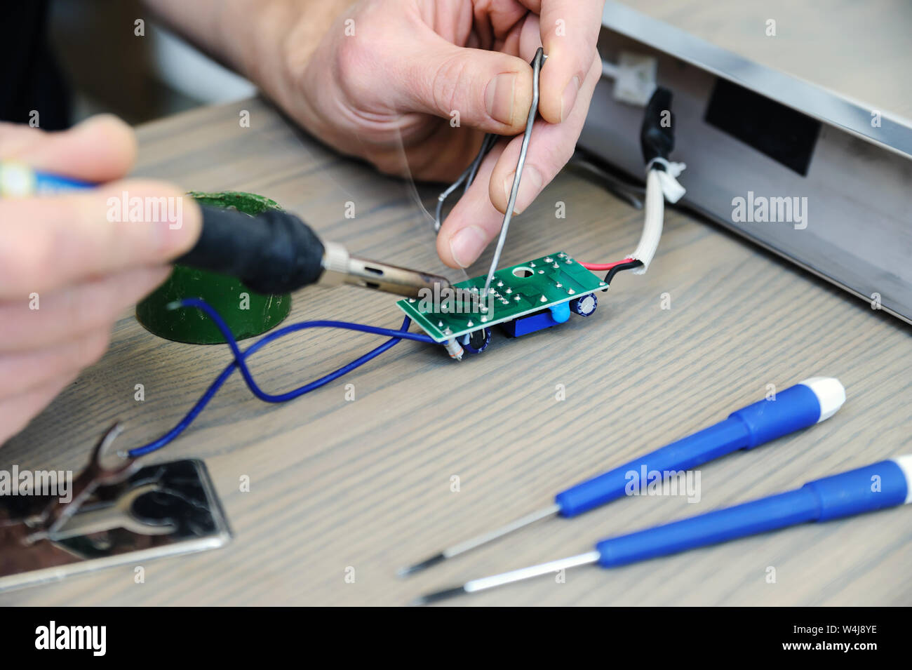 The man is repairing the power supply of the lamp. He is holding an ...