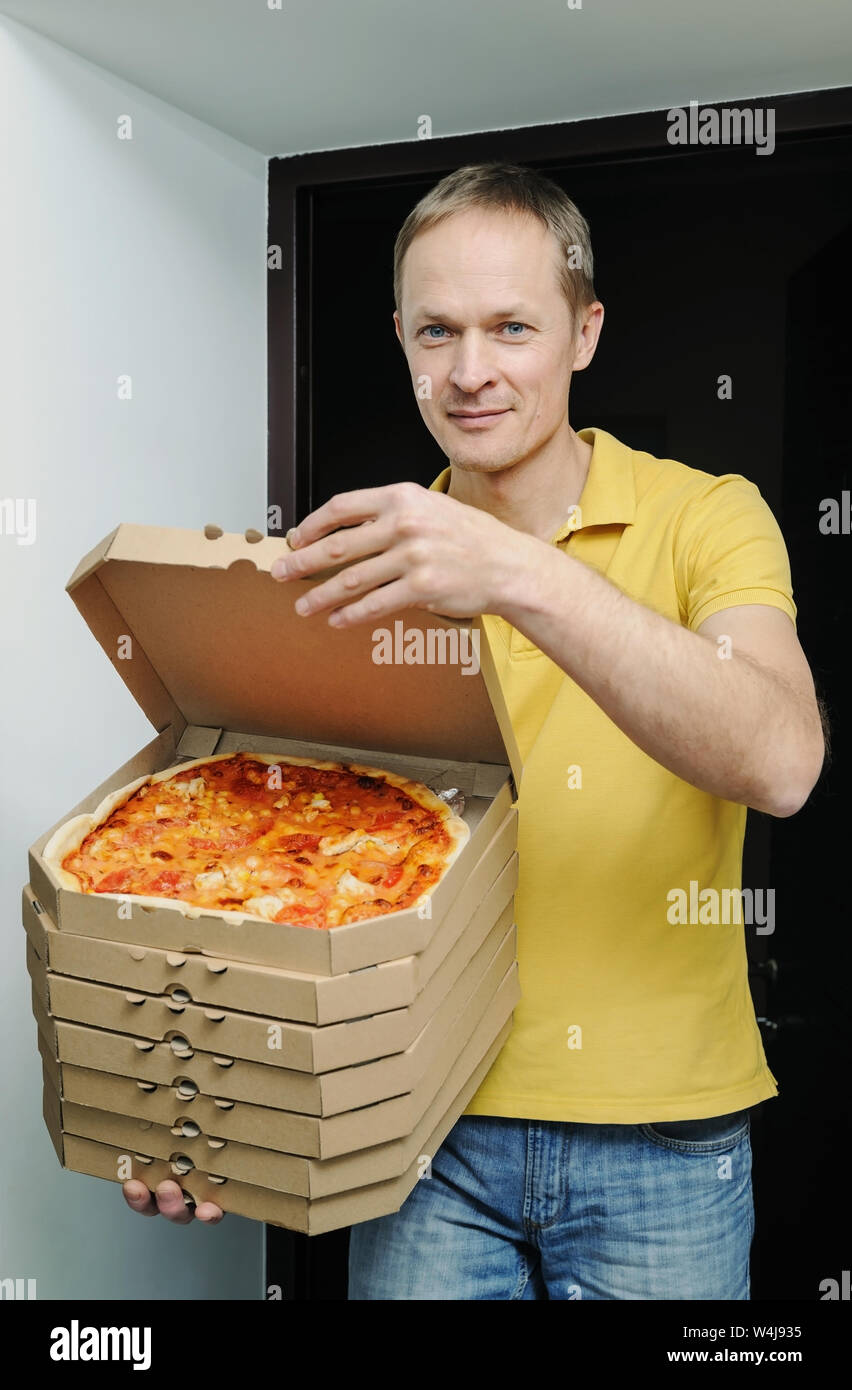 Food delivery home. The man is holding boxes with pizzas in the doorway