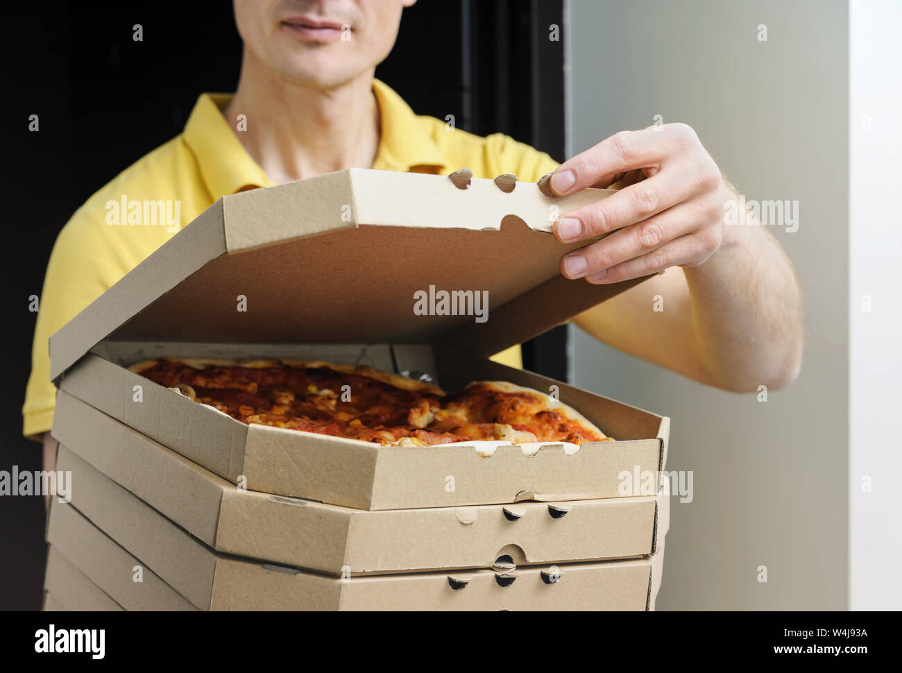 Food delivery home. The man is holding boxes with pizzas in the doorway