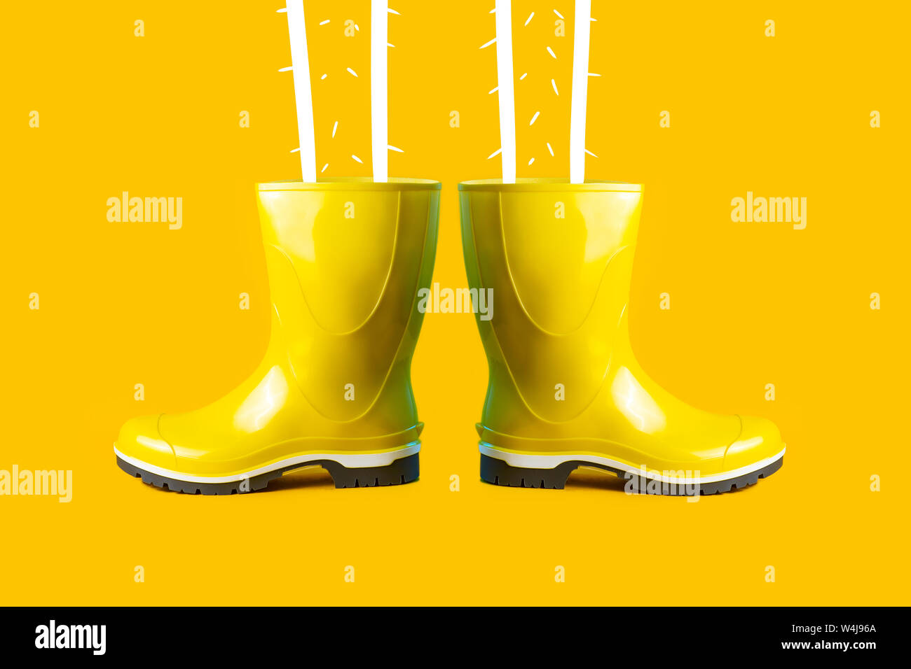 autumn composition of yellow rubber boots and feet on a yellow ...