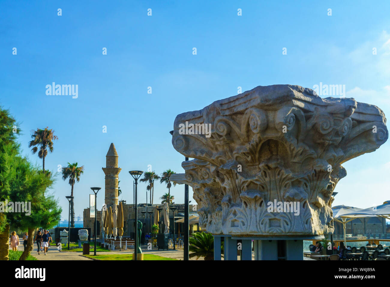 Caesarea, Israel - July 22, 2019: View of a Roma era column capital, and the Bosnian mosque, with visitors, in Caesarea National Park, Northern Israel Stock Photo
