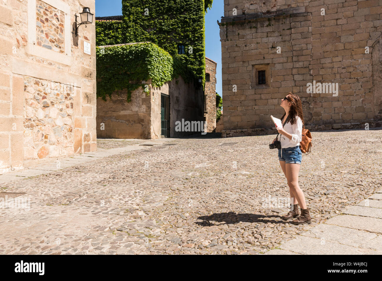 A young red-haired tourist checks a map of the city next to the famous Hotel-Restaurant Atrio in Caceres Stock Photo